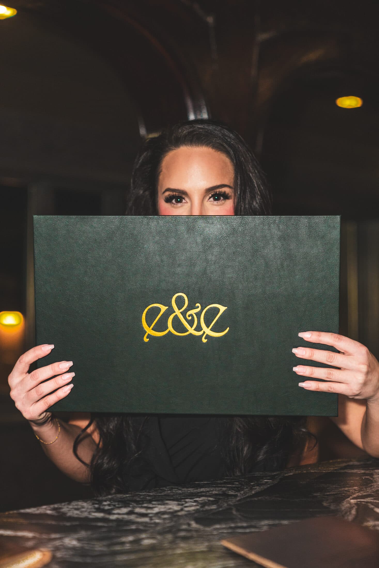 A guest with the embossed Ember & Eagle menu at the bar