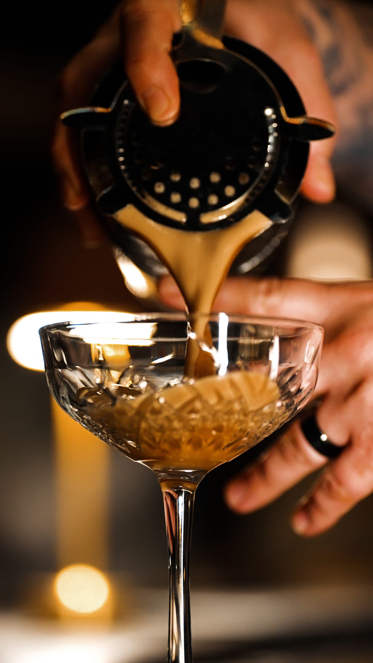 A cocktail poured into a coupe over candlelight at Ember & Eagle