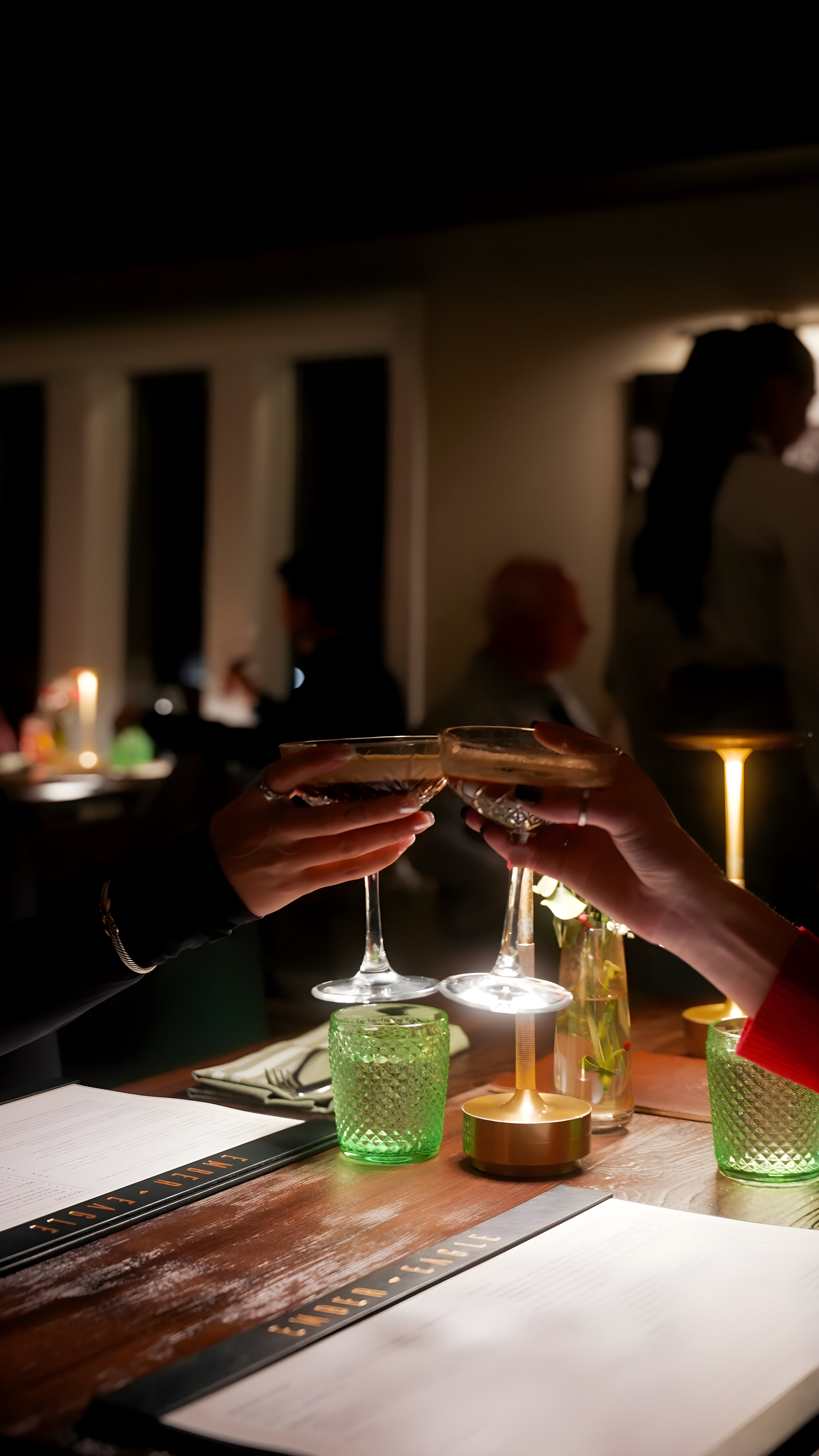 A couple toasting at a candlelit table at Ember & Eagle